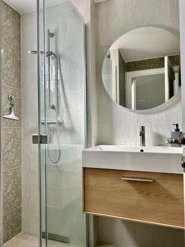 une salle de bain avec un lavabo et une douche avec un miroir dans l'établissement Les Restanques 30 chênes, à Grimaud