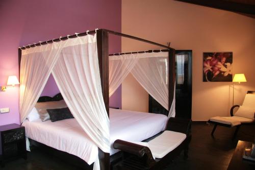 a bedroom with two beds with curtains and a chair at Eco Hotel Boutique & Spa Capitulo Trece - Adults Only in Maderuelo