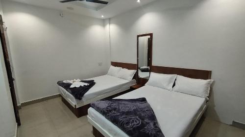 Duas camas num pequeno quarto com um espelho em Shree Govindam Guest House em Ujaim
