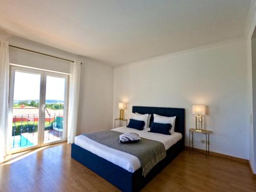 a bedroom with a large bed and a large window at Casa Beloura between the sea and the mountains in Sintra