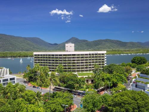 a hotel with a lake and mountains in the background at Hilton Cairns in Cairns