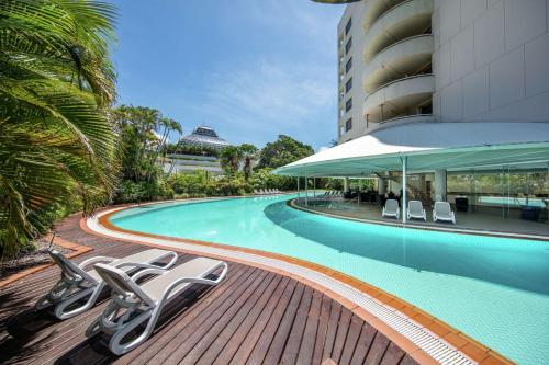 een zwembad met ligstoelen naast een gebouw bij Hilton Cairns in Cairns