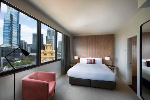 1 dormitorio con cama, silla y ventana grande en DoubleTree by Hilton Melbourne, en Melbourne