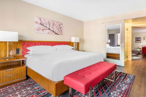 a bedroom with a large bed and a red bench at Hilton Club The District Washington DC in Washington, D.C.