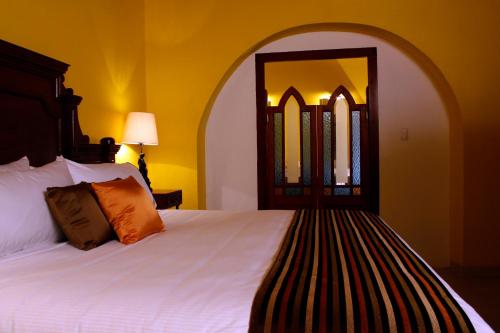 a bedroom with a white bed with a large mirror at Hotel Boutique Casa Don Gustavo, Campeche in Campeche