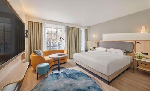 um quarto com uma grande cama branca e uma cadeira em Hyatt Regency London Blackfriars em Londres