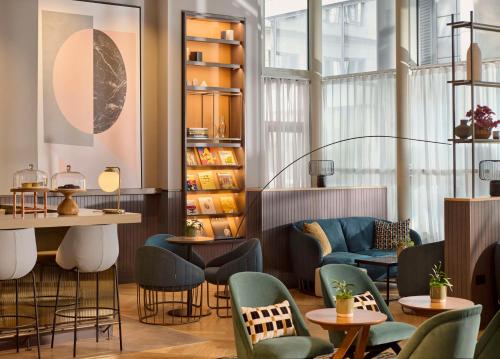 a restaurant with chairs and tables and a shelf with books at Hyatt Regency London Blackfriars in London