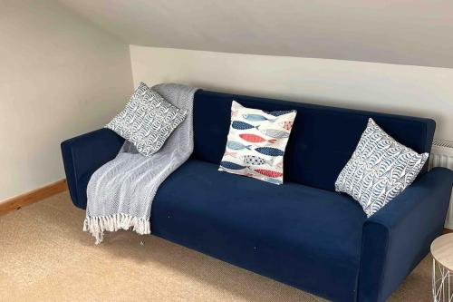 a blue couch with pillows on it in a room at The Surf House (Widemouth Bay) in Bude