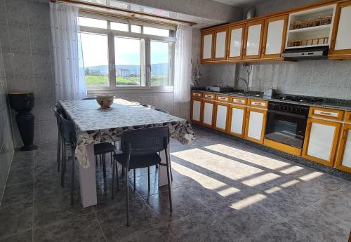 een keuken met een tafel met stoelen en een raam bij Vento Nordés in Malpica