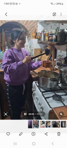 a woman standing in a kitchen preparing food on a stove at Hatzikyprianou Museum Studio in Lazania
