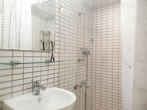 a white tiled bathroom with a sink and a mirror at COZY Home in Taipei