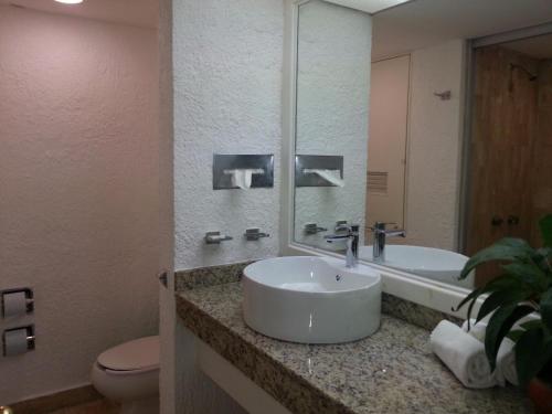 a bathroom with a sink and a toilet and a mirror at Cancun Studio overlooking the Lagoon in Cancún