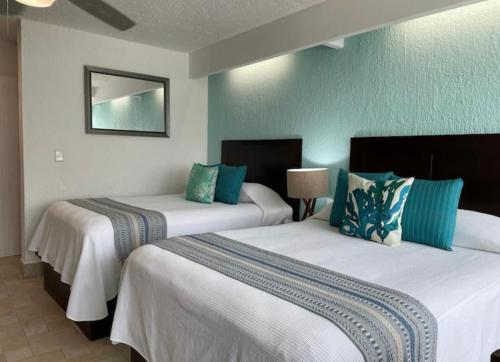 two beds in a room with blue and white at Cancun Studio overlooking the Lagoon in Cancún