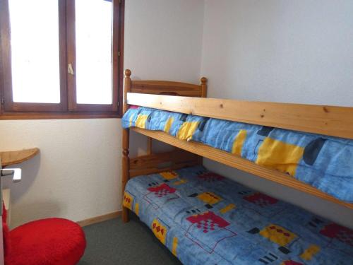 - une chambre avec des lits superposés et une chaise rouge dans l'établissement Chalet familial 6 pers. à 800m des remontées mécaniques - Saint-Lary-Soulan. - FR-1-457-243, à Saint-Lary-Soulan