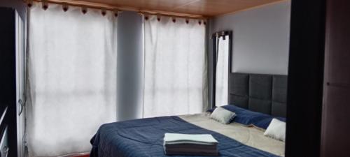 Schlafzimmer mit einem Bett mit blauer Bettwäsche und Fenstern in der Unterkunft Tranquilo baño privado in Chía