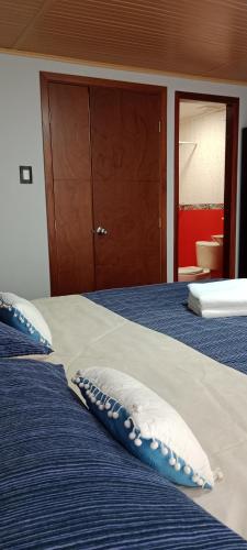 a bed with blue and white pillows on it at Tranquilo baño privado in Chía