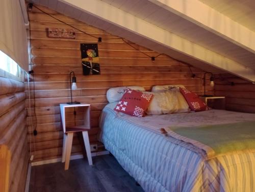 una camera con un letto su una parete in legno di Mini Casa de Troncos en el Sur a San Martín de los Andes