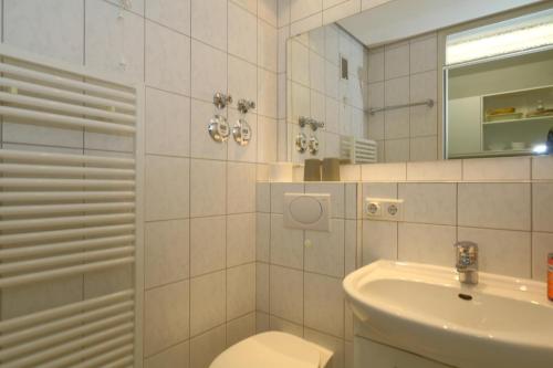 a bathroom with a sink and a toilet and a mirror at Haus Sylter Welle 9-92a OB in Westerland (Sylt)