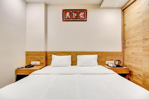 a bedroom with a large white bed and a clock on the wall at FabHotel Manjeet in Bhopal