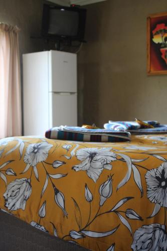 a bed with an orange blanket with flowers on it at Emahlathini Guest Farm in Piet Retief