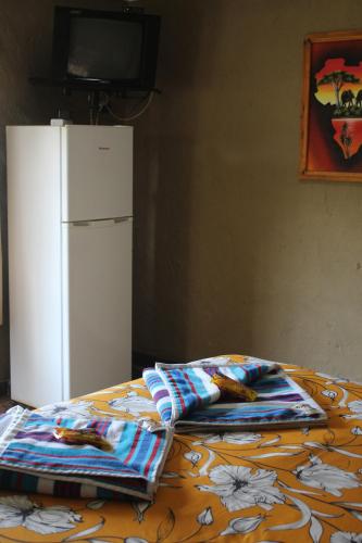 a bed with two pillows and a white refrigerator at Emahlathini Guest Farm in Piet Retief