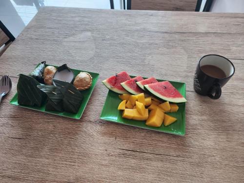 two green plates with fruit and a cup of coffee at Connexion in Ko Yao Noi
