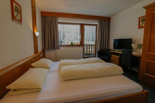 a hotel room with two beds and a desk at Hotel Tia Apart in Kaunertal