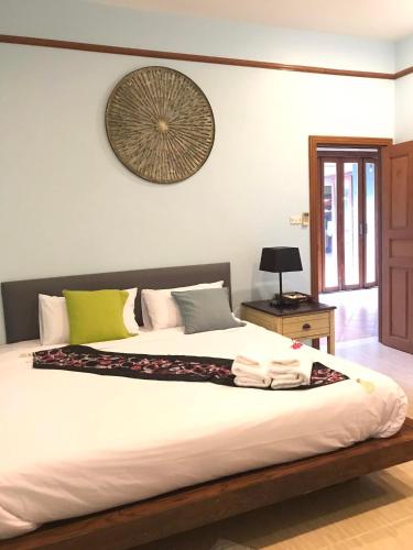 a bedroom with a large bed with a clock on the wall at Plumeria Villa Thalang in Ban Pak Lak