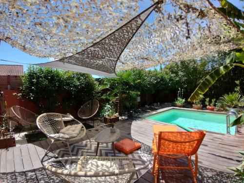une terrasse avec des chaises et un parasol ainsi qu'une piscine dans l'établissement Studio rouge Lagon, à Romans-sur-Isère