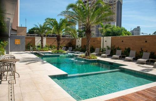 una piscina con sillas y palmeras en un edificio en Hotel Rafain Centro, en Foz do Iguaçu