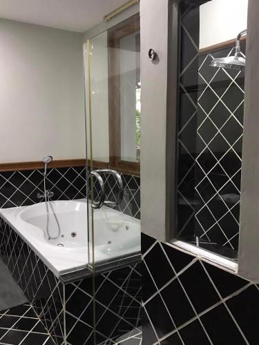 a black and white bathroom with a tub and a mirror at Plumeria Villa Thalang in Ban Pak Lak