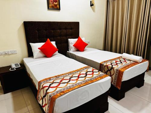 two beds in a hotel room with red pillows at Hotel NorthWay in Vavuniya