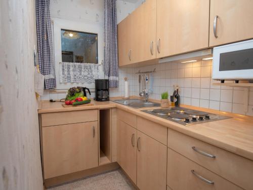 a kitchen with wooden cabinets and a sink and a microwave at Holiday Home Windrad by Interhome in Norddeich