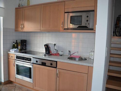 a kitchen with wooden cabinets and a sink and a microwave at Großer Wattläufer in Welt