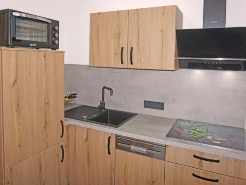 a kitchen with wooden cabinets and a sink and a microwave at Apartment Susi by Interhome in Flirsch