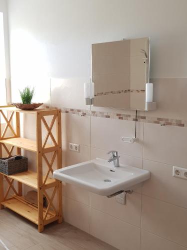 a white bathroom with a sink and a mirror at Nordergeest EG in Tating