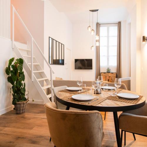 a dining room with a table and chairs and a staircase at Le Laurencin Sens - La Mezzanine - Cœur de ville in Sens