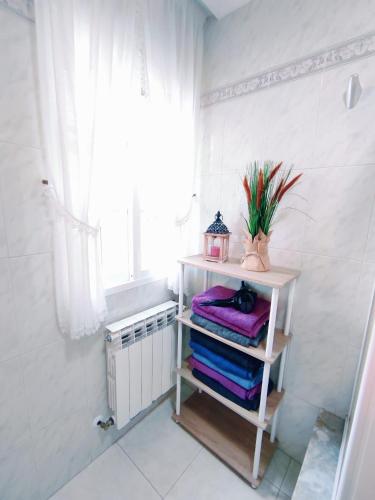 a bathroom with a shelf with towels and a window at CASA GLORIA - ÁTICO BALCÓN in Combarro