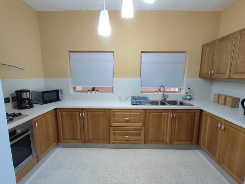 a kitchen with wooden cabinets and a sink at Dolphin Court 3-Bedroom Sea View Apartment in Marsaskala, Malta in Marsaskala