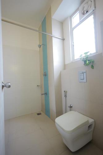 a bathroom with a toilet and a shower with a window at Ixora Suites in Bengaluru