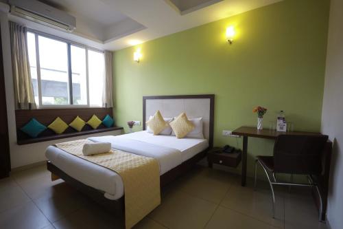 a bedroom with a bed and a desk with a chair at Ixora Suites in Bangalore