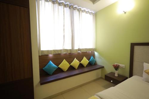 a bedroom with a window with blue and yellow pillows at Ixora Suites in Bengaluru