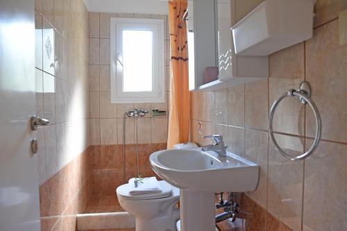 bagno con lavandino, servizi igienici e finestra di Butterfly Barbati apartments a Barbati