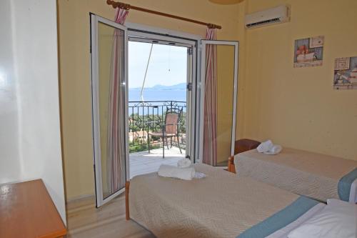 a room with two beds and a door with a balcony at Butterfly Barbati apartments in Barbati