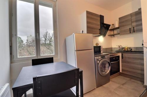 uma cozinha com um frigorífico e uma mesa com uma mesa; em Appart du Pont Vert A12 proche centre - Mon Groom em Troyes