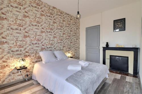 sypialnia z białym łóżkiem i ceglaną ścianą w obiekcie Appart du Pont Vert A12 proche centre - Mon Groom w Troyes