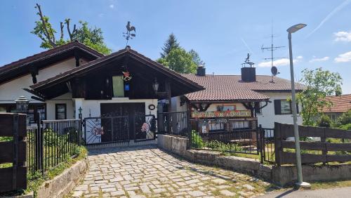 a white house with a black gate and a driveway at Ferienhäuser zum Badeweiher in Neuschönau