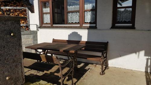 a picnic table and a bench in front of a building at Ferienhäuser zum Badeweiher in Neuschönau