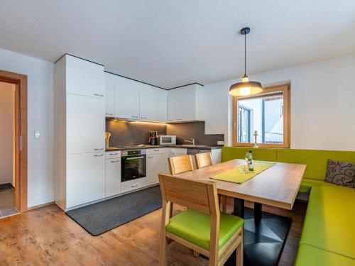 kuchnia z drewnianym stołem i zielonymi krzesłami w obiekcie Apartment Martina-1 by Interhome w mieście Kappl