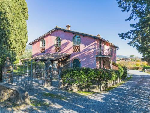 uma casa cor-de-rosa com uma vedação à frente. em Apartment Le Fornaci-1 by Interhome em San Quirico di Moriano